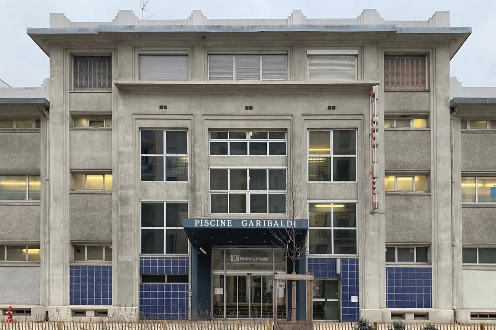 Façade de la piscine Garibaldi à Lyon, béton clair et carreaux bleus